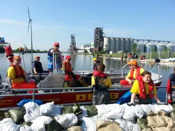 DLRG Bootsbesatzung wartet auf die nächsten Sandsäcke