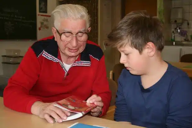 Anton (rechts) liest aus „Flockis Abenteuer“, einem Buch des Kinder- und Jugendbuchautors Achim Bröger. Lesepate Wolfgang Stephani ist begeistert von den Fortschritten, die sein Schüler dank des regelmäßigen Lesens macht (Foto: Gemeinde Neunkirchen).