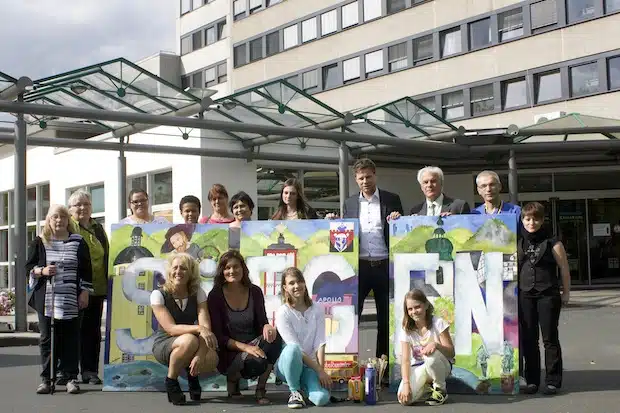 In einem feierlichen Rahmen präsentierten Projektteilnehmer, die Initiatorinnen Ilona Weber und Barbara Quast (kniend von links) sowie Sozialdienste-Geschäftsführer Daniel Imhäuser, Klinikums-Geschäftsführer Hubert Becher und der Ärztliche Direktor Professor Berthold Hell (stehend von links) das Kunstwerk - Quelle: Diakonie in Südwestfalen gGmbH.