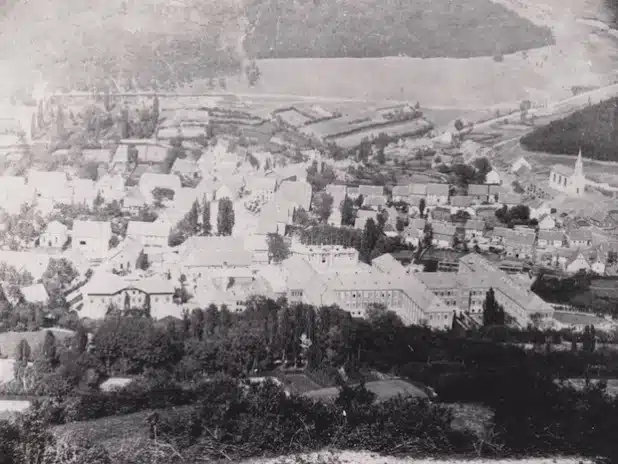 Das Foto wurde um das Jahr 1872 aufgenommen. Man schaut auf Niedermarsberg. Im Vordergrund sind die Gebäude der Westfälischen Klinik in doppelter „H-Form“ zu sehen. Hinter dem linken „H“ wird gerade die Anstaltskirche auf der ehemaligen Bleichwiese erbaut. Sie wurde aus dem Steinmaterial des Chores der alten Klosterkirche erstellt (Quelle: Marsberger Geschichten - Schlüssel zur Vergangenheit e.V.).