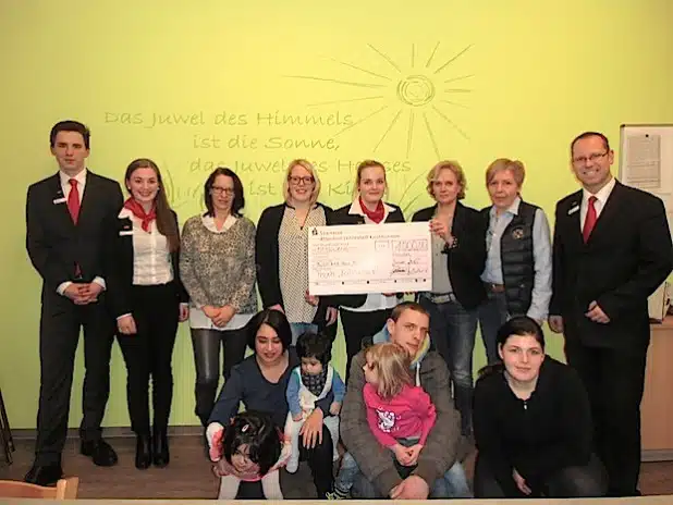 Das Bild zeigt drei der Auszubildenden und Ausbildungsleiter Thomas Vahland (rechts) bei der Scheckübergabe im Mutter-Kind-Haus (Foto: Sparkasse Attendorn-Lennestadt-Kirchhundem).