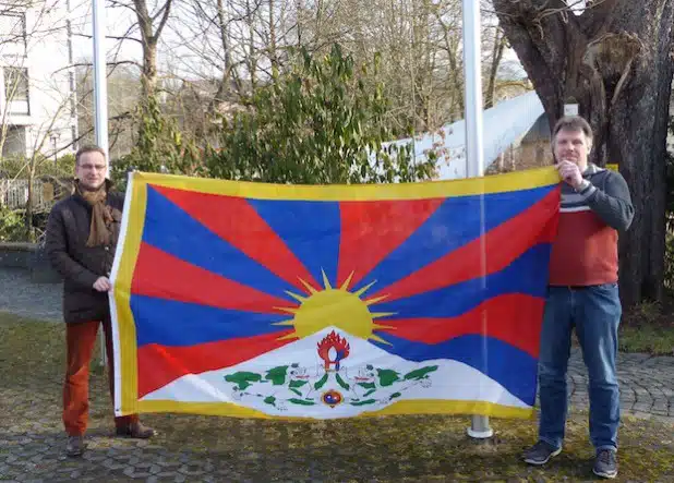 Bürgermeister Hans-Peter Hasenstab und sein Mitarbeiter Karsten Valenta präsentieren vor dem Hissen die Flagge Tibets am Marktplatz (Foto: Stadt Hilchenbach).