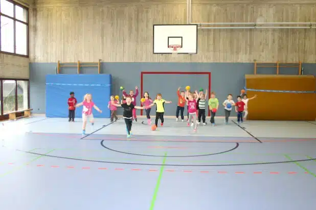 Die Erstklässler toben vergnügt über den frisch renovierten Hallenboden der Sporthalle der Mariengrundschule (Foto: Stadt Meschede).