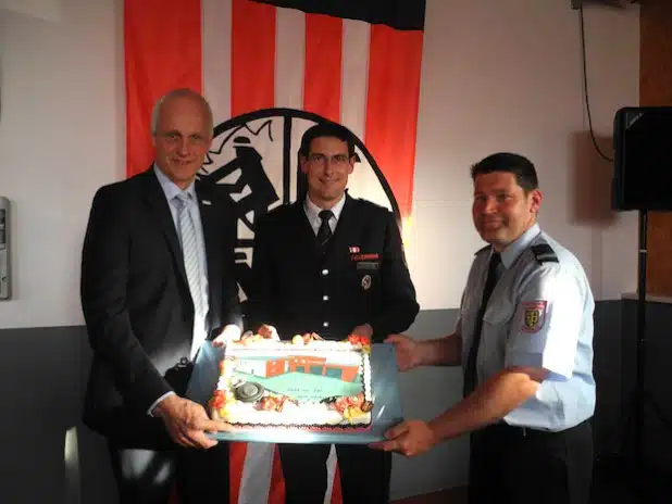 Am Freitag wurde in Lippe das neue Feuerwehrgerätehaus eingeweiht. Anstatt eines Schlüssels überreichte Bürgermeister Christoph Ewers einen Kuchen an Wehrführer Tobias Klein (mi.) und Lippes Löschzugführer Jens Wildfeuer (re.) - Foto: Gemeinde Burbach.