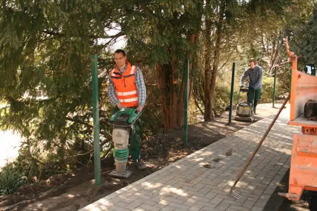 Zwei Mitarbeiter des Bauhofs bei der Verdichtung der Erde im Außenbereich des Kindergartens „Kunterbunt“ (Foto: Gemeinde Neunkirchen).