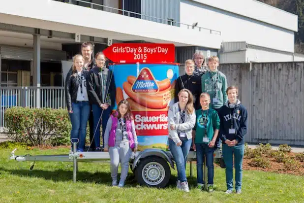 Die Teilnehmerinnen und Teilnehmer des Girls‘ Day und Boys‘ Day 2015 mit der Personalleiterin Petra Palla sowie dem bekanntesten Produkt der Firma Metten, die „Dicke Sauerländer“ Bockwurst (Foto: Metten Fleischwaren GmbH & Co. KG).