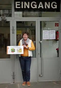 Empfangsdame Ursula Albers mit dem neuen Schild als Einrichtung des nationalen Geopark GrenzWelten (Foto: Bergbaumuseum Ramsbeck GmbH)