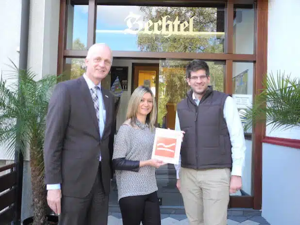 Bürgermeister Christoph Ewers (links) und Tourismusreferent Johannes Werthenbach (rechts) überreichten jetzt das offizielle Schild über die Zertifizierung als „Qualitätsbetrieb Rothaarsteig“ an Hotelleiterin Antonija Cosic (Mitte) - Foto: Gemeinde Burbach.