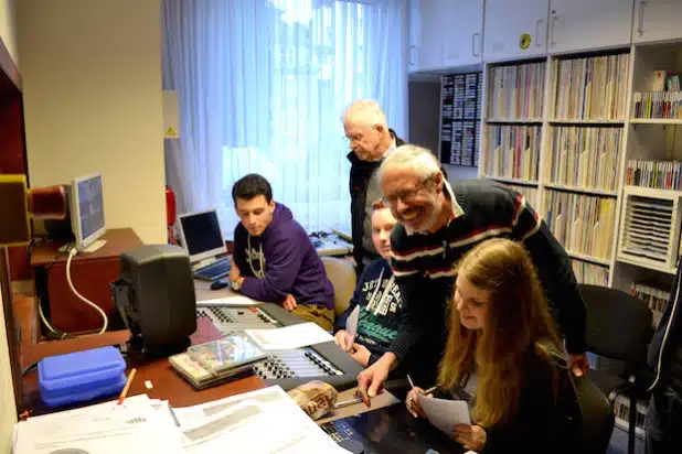 Die Initiatoren des Krankenhausrundfunks zum Jubiläum vereint: Jonny Boehm (vorne) und Jürgen Becker schauen den Schülern zur Jubiläumssendung über die Schulter - Foto: Katholische Hospitalgesellschaft Südwestfalen gGmbH.