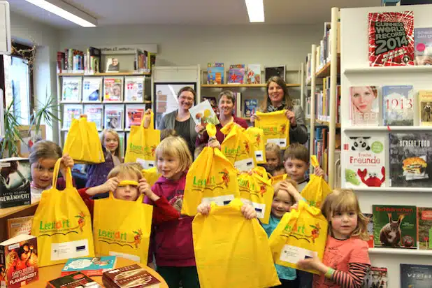 Die Bibliothek Wilnsdorf ist Partner des Programms „Lesestart“. Bürgermeisterin Christa Schuppler (im Hintergrund rechts), Bibliotheksleiterin Sabine Flecke (Mitte) sowie Vorlesepatin Christiane Heupel verschenkten leuchtend gelbe Lesefreude (Foto: Gemeinde Wilnsdorf).